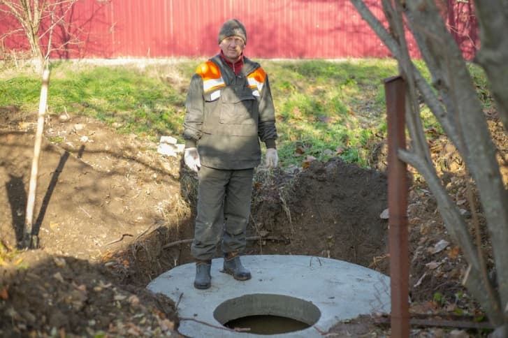 mężczyzna stojący na betonowym szambie